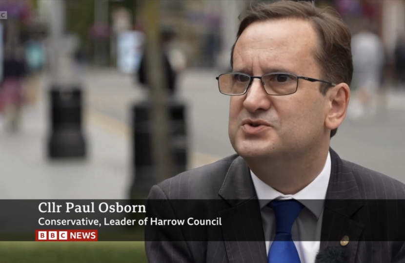 Cllr Osborn, dressed in a suit and tie, being interviewed by the BBC in Harrow Town Centre