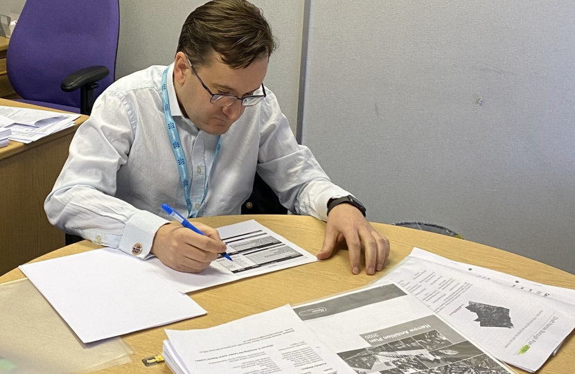 Cllr Paul Osborn sat at his desk working on the budget. There are multiple documents on the desk in front of him.