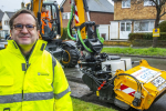 Cllr Osborn stood in front of the Council's new JCB pothole pro machine in a road which has been resurfaced.