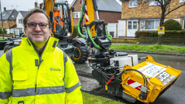 Cllr Osborn stood in front of the Council's new JCB pothole pro machine in a road which has been resurfaced.