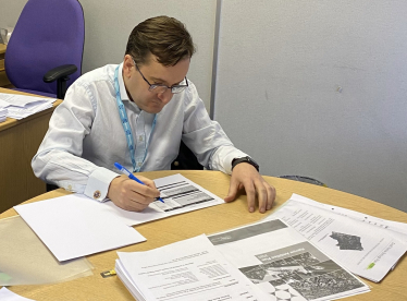 Cllr Paul Osborn sat at his desk working on the budget. There are multiple documents on the desk in front of him.