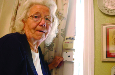 A pensioner standing by their front door.